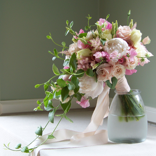 hand tied, cascade bridal bouquet containing peonies, sweet peas, astilbe, lisianthus, dahlias, Eos roses, Sweet Eskimo roses, White Mikado spray roses, and foliage cut from the garden