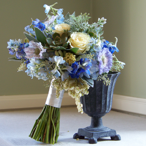 bridal bouquet containing delphinium, blue scabiosa, tweedia, hydrangea, pieris, tuberose, Cream Prophyta roses, seeded eucalyptus, silver tree, wormwood, and succulents