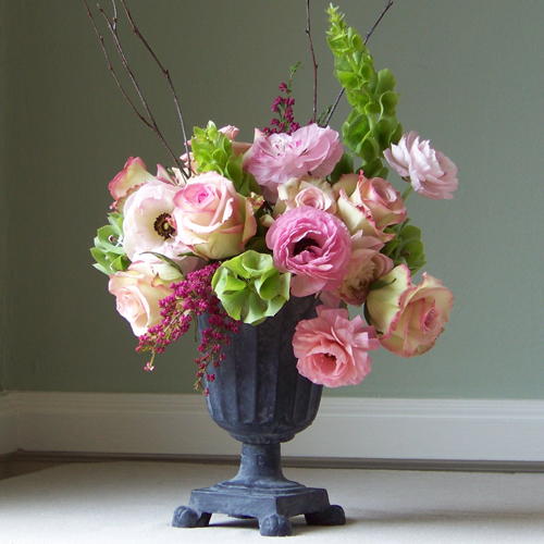 centerpiece with bells of Ireland, Cezanne roses, pink ranunculus, heather and birch branches in a cast iron urn