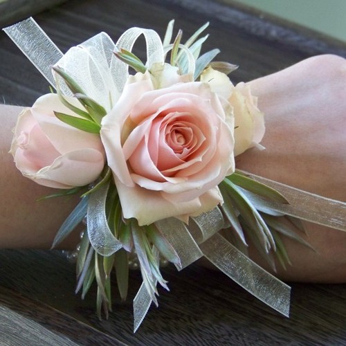 wrist corsage with Star Blush spray roses, green leucadendron and ivory chiffon ribbon on an ivory pearl bracelet