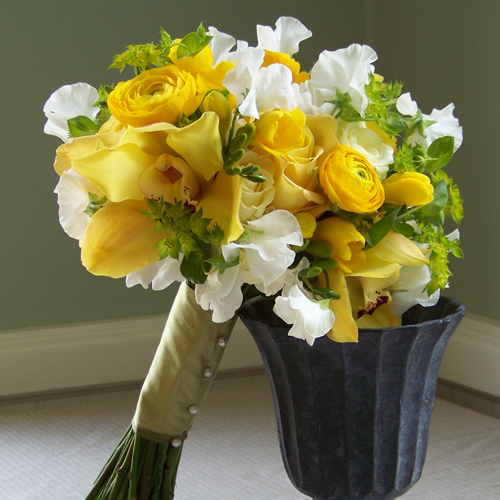 Hand-tied bouquet with yellow cymbidium orchids, yellow ranunculus, yellow freesia, Beach sweetheart roses, white sweet peas and bupleurum