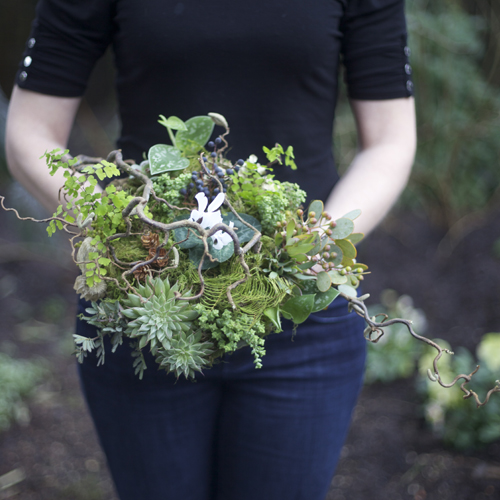 woodland bridal bouquet with contorted filbert branches, privet berries, acacia foliage, pinecones, white cyclamen, green leucadendron, Philodendron 'Silver Cloud', sea star fern, maiden hair fern, seeded eucalyptus, Graptoveria 'Silver Star', Crassula rupestris subsp. marnieriana, sponge mushrooms, lichen and moss, with a eucalyptus and river birch bark handle treatment